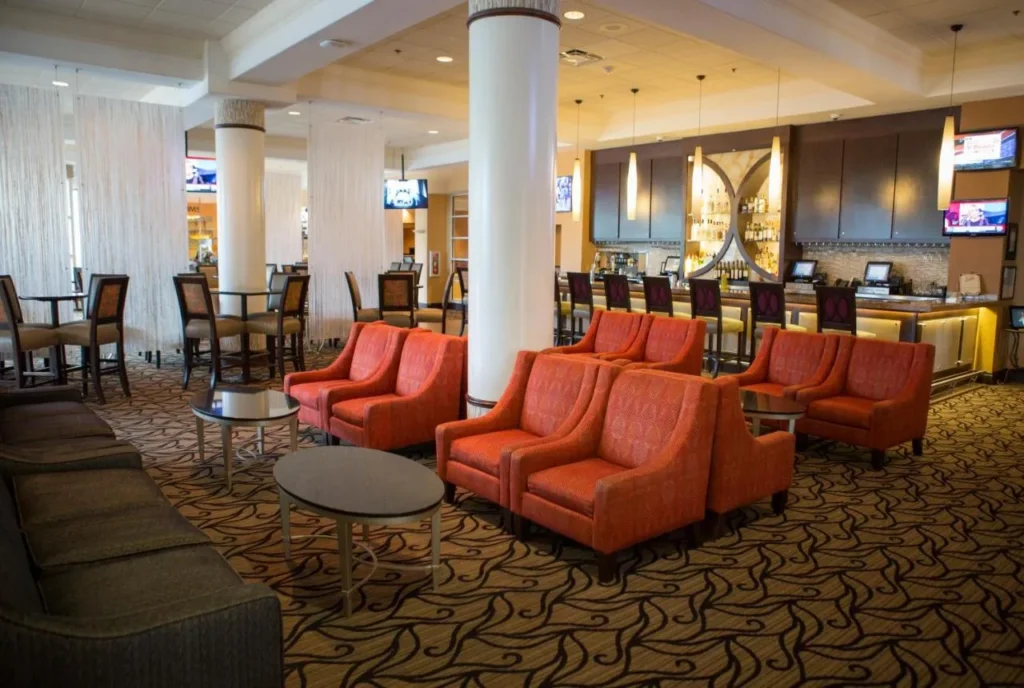 Lobby bar lounge with orange armchairs, high tables and bar counter at Rosen Plaza Hotel