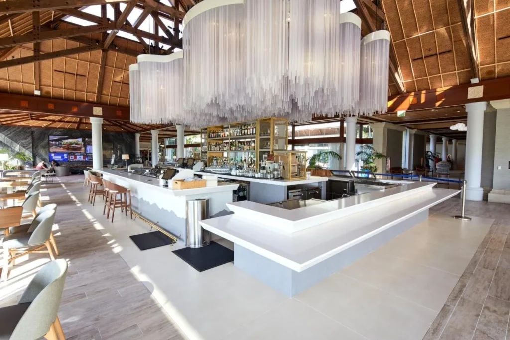 Bar en el vest&iacute;bulo bajo un alto techo de madera de estilo con techo de paja en Loews Royal Pacific Resort