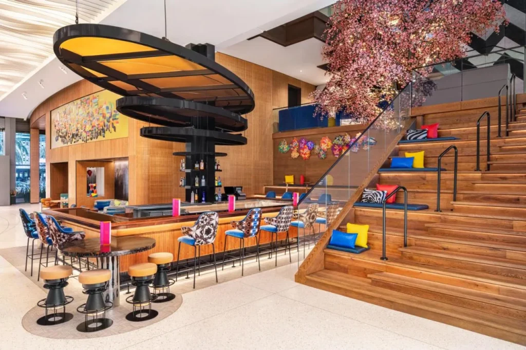 Bar en el vest&iacute;bulo con taburetes estampados junto a una escalera de madera acolchada en Lake Nona Wave Hotel