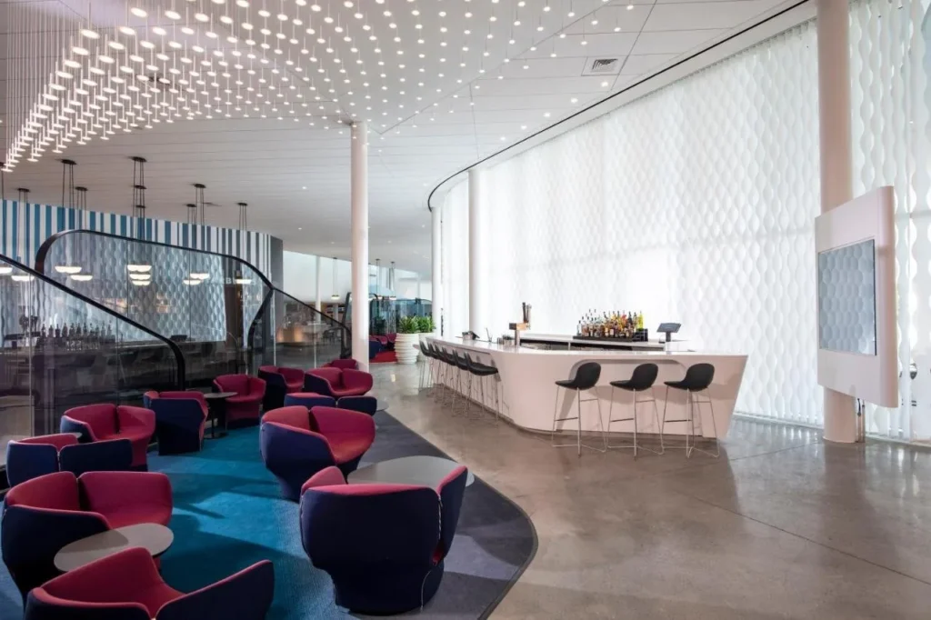 Lobby lounge y bar en el Hotel Universal Aventura con sillones rojos y azul marino bajo techo iluminado