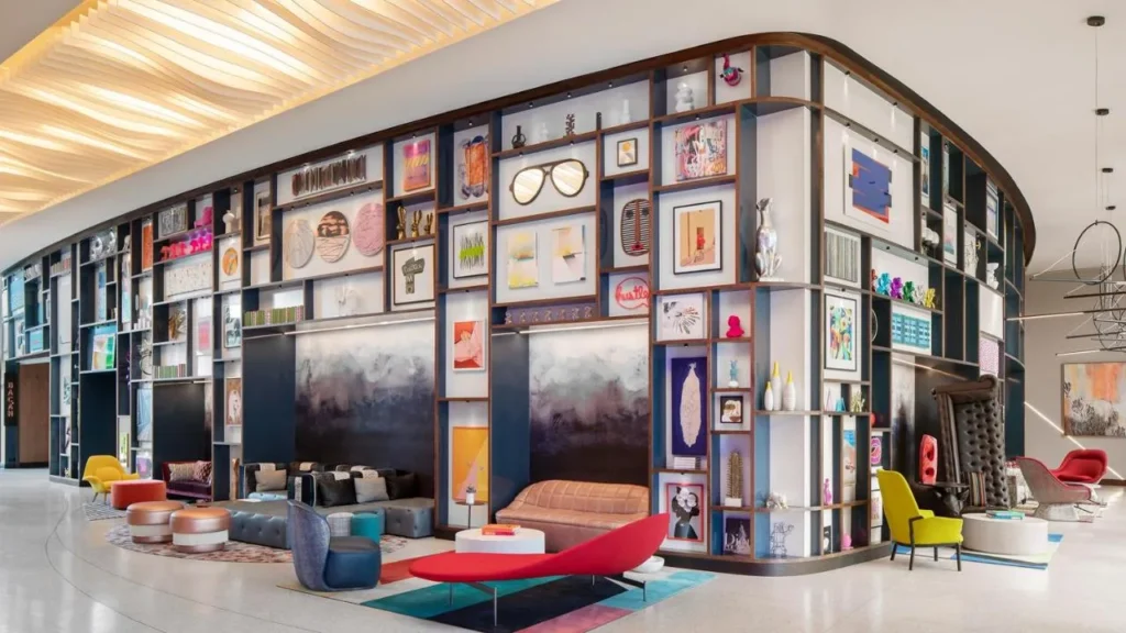 Sal&oacute;n del vest&iacute;bulo con una pared curva de obras de arte y asientos coloridos en el Lake Nona Wave Hotel