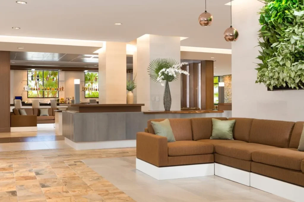 Salón del vestíbulo con sofá seccional, pared de plantas verdes y bar más allá en The Grove Resort