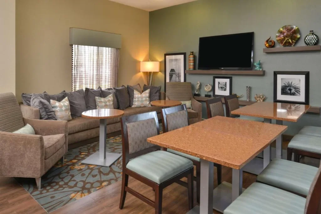 Lobby lounge with a sofa, armchairs, wall TV and tables at Hampton Inn Closest to Universal