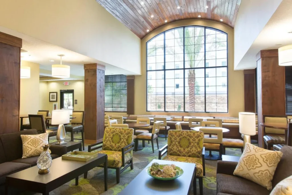 Salón en el vestíbulo con sillones y una ventana arqueada alta en Staybridge Suites Orlando at SeaWorld