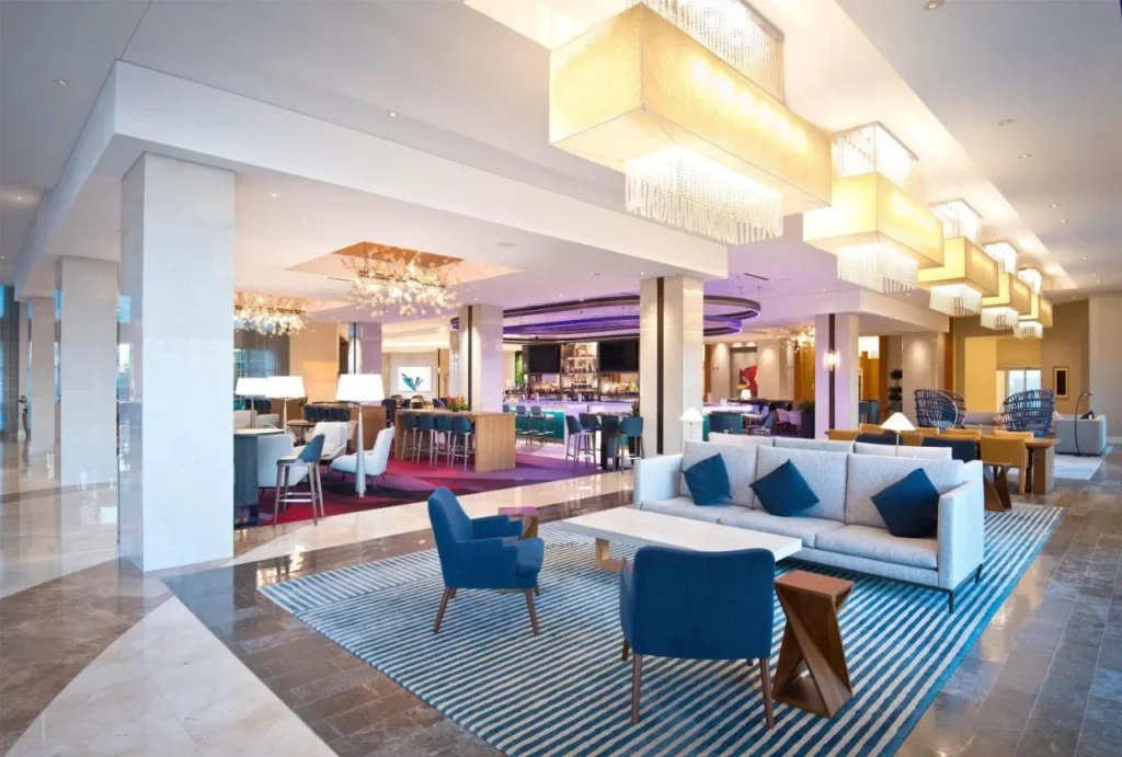 Lobby lounge with blue armchairs, crystal pendant lights and a bar beyond at Hilton Orlando