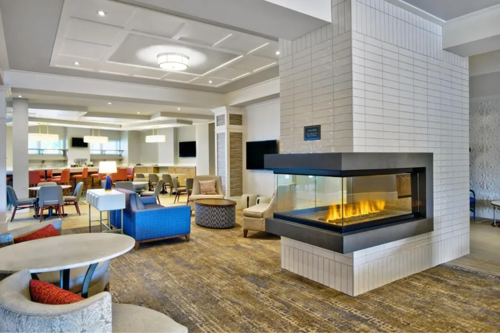 Sal&oacute;n en el vest&iacute;bulo con sof&aacute; azul, sillones y chimenea de cristal en el Residence Inn Flamingo Crossings