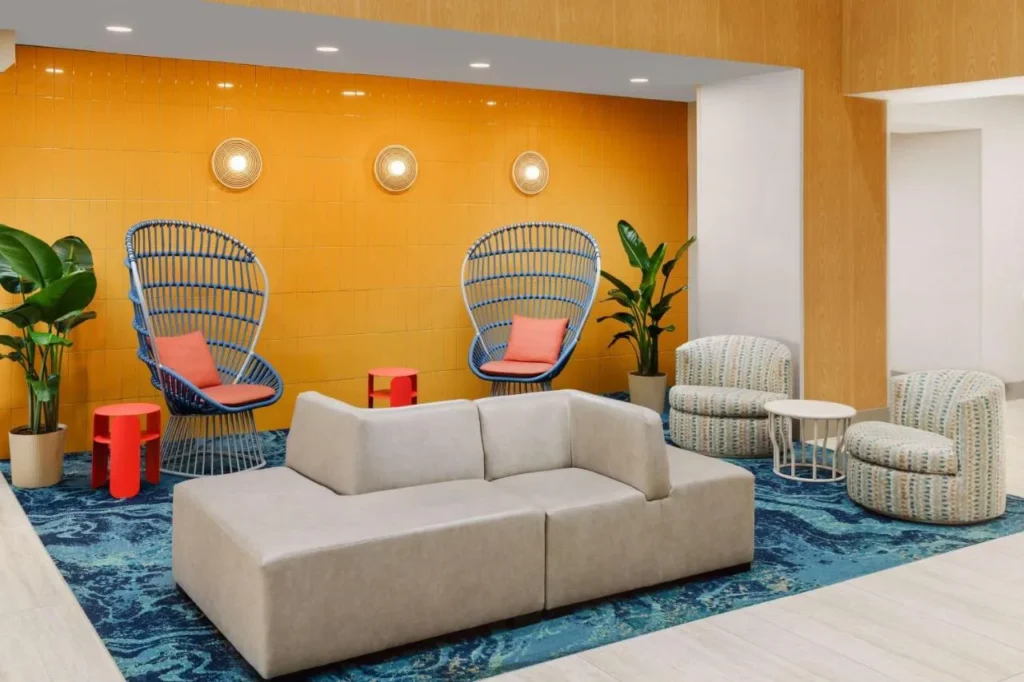 Salón del vestíbulo con sillas de mimbre azul y azulejos naranjas en Hyatt Place across from Universal