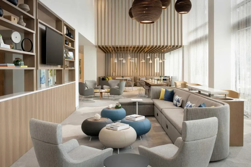 Salón en el vestíbulo con sofá curvo, sillones y ventanas altas en Element Orlando Universal Blvd.