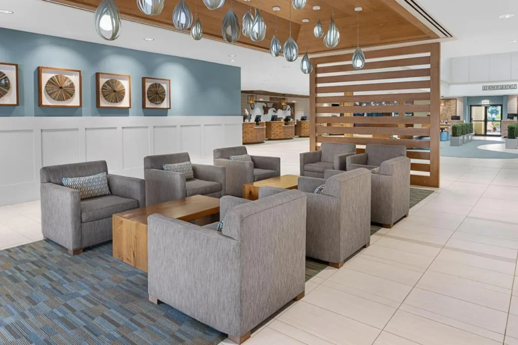 Salón del vestíbulo con sillones grises y luces colgantes cerca de la recepción en Sheraton Vistana Resort Villas
