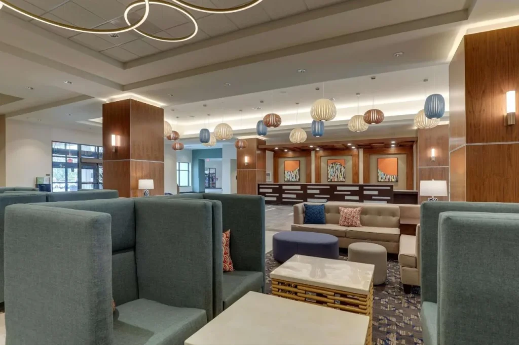 Lobby lounge with high-backed teal chairs, sofas and pendant lights at Drury Plaza Hotel Orlando