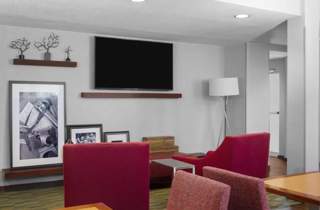Lobby lounge with red armchairs and a wall TV at Hampton Inn Orlando/Lake Buena Vista