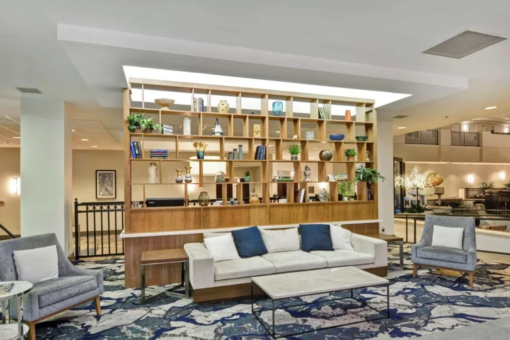 Lobby lounge with sofa, armchairs and display shelving at Embassy Suites Orlando Downtown