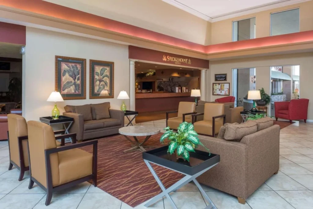 Lobby lounge with sofas and armchairs beside the Smokehouse Grill at Ramada Kissimmee Gateway