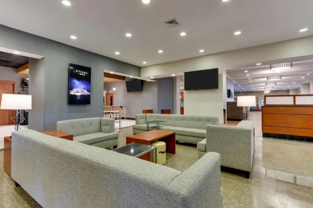 Lobby lounge with sofas, armchairs and TVs at Drury Inn & Suites near Universal Orlando