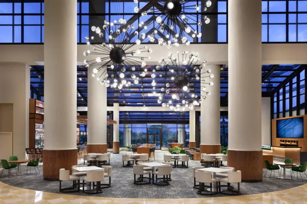 Sal&oacute;n del vest&iacute;bulo con columnas altas, techo de cristal y candelabros Starburst en el Orlando World Center Marriott
