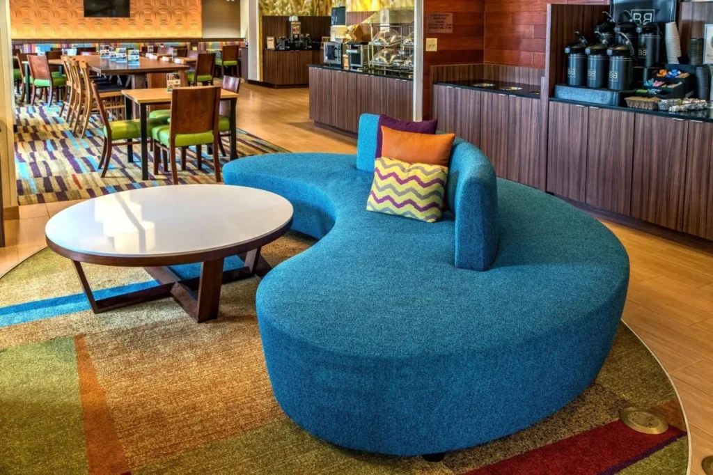 Lobby seating beside the breakfast counter and dining tables at Fairfield Inn & Suites Near Universal
