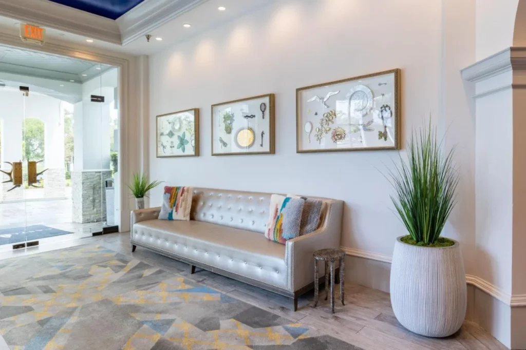 Lobby seating with a silver tufted sofa and framed curio art at Castle Hotel Orlando