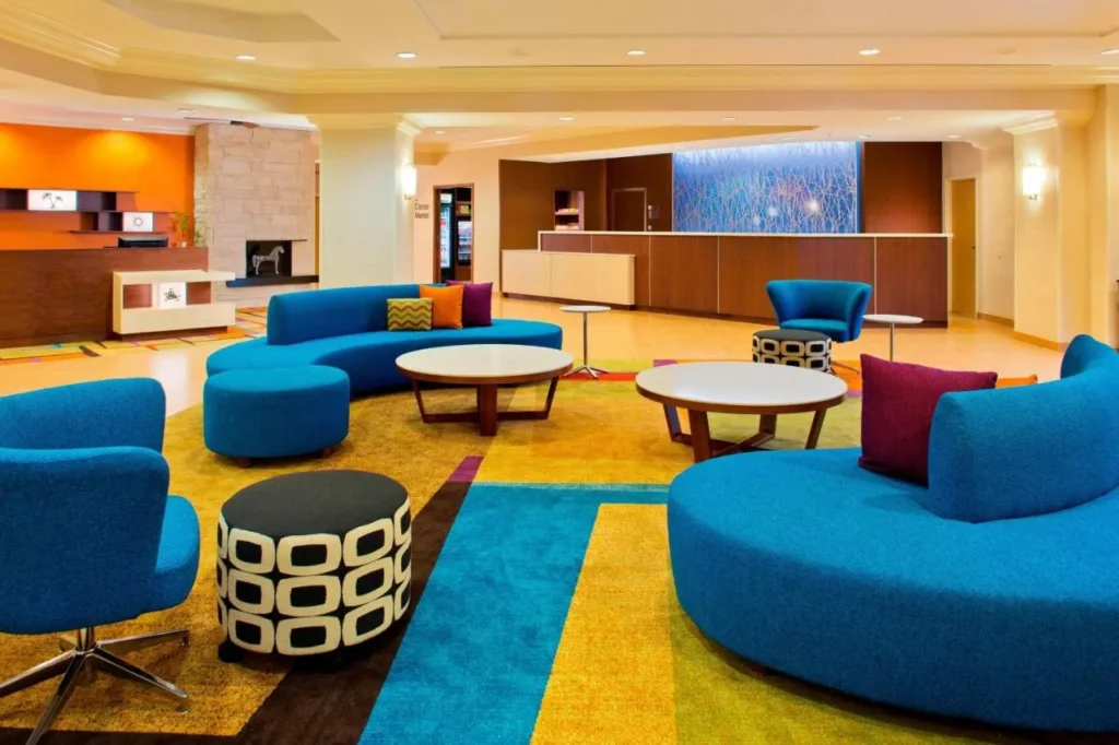 Asientos en el vest&iacute;bulo con sof&aacute;s azules y mesas redondas en Fairfield Inn & Suites Marriott Village