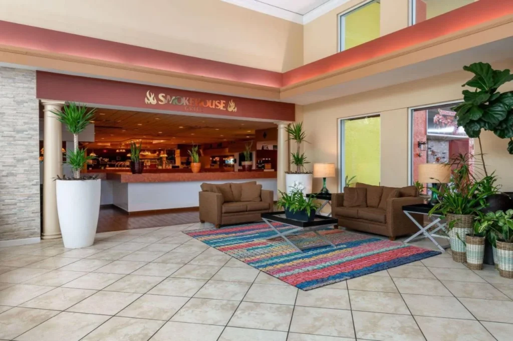 Lobby con sof&aacute;s marrones junto a la entrada de Smokehouse Grill en Ramada by Wyndham Kissimmee Gateway