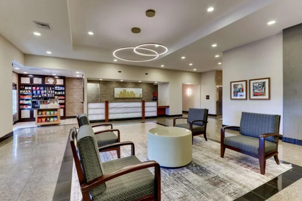 Lobby with front desk, snack market and armchairs at Drury Inn & Suites near Universal