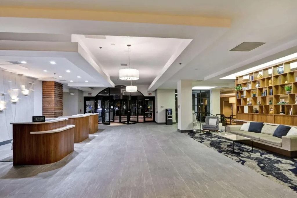 Lobby with front desks, revolving doors and bookshelf lounge at Embassy Suites Orlando Downtown