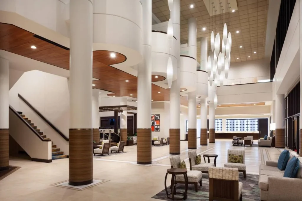 Lobby con altas columnas blancas, luces colgantes y asientos en el Marriott Orlando Airport Lakeside