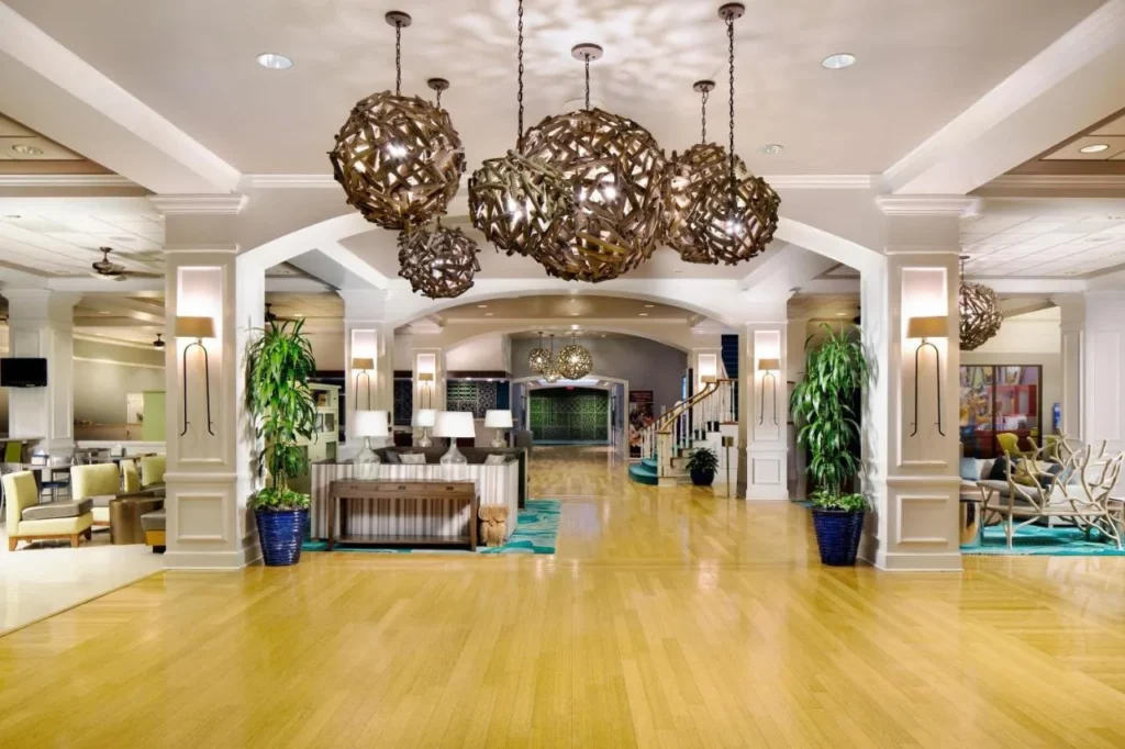 Lobby con luces colgantes tejidas, columnas blancas y pisos de madera en Wyndham Lake Buena Vista
