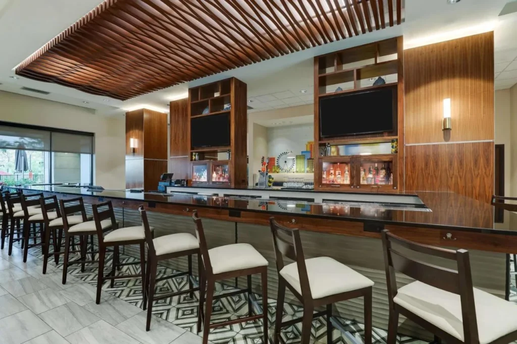 Barra de bar larga con taburetes blancos en Drury Plaza Hotel Orlando