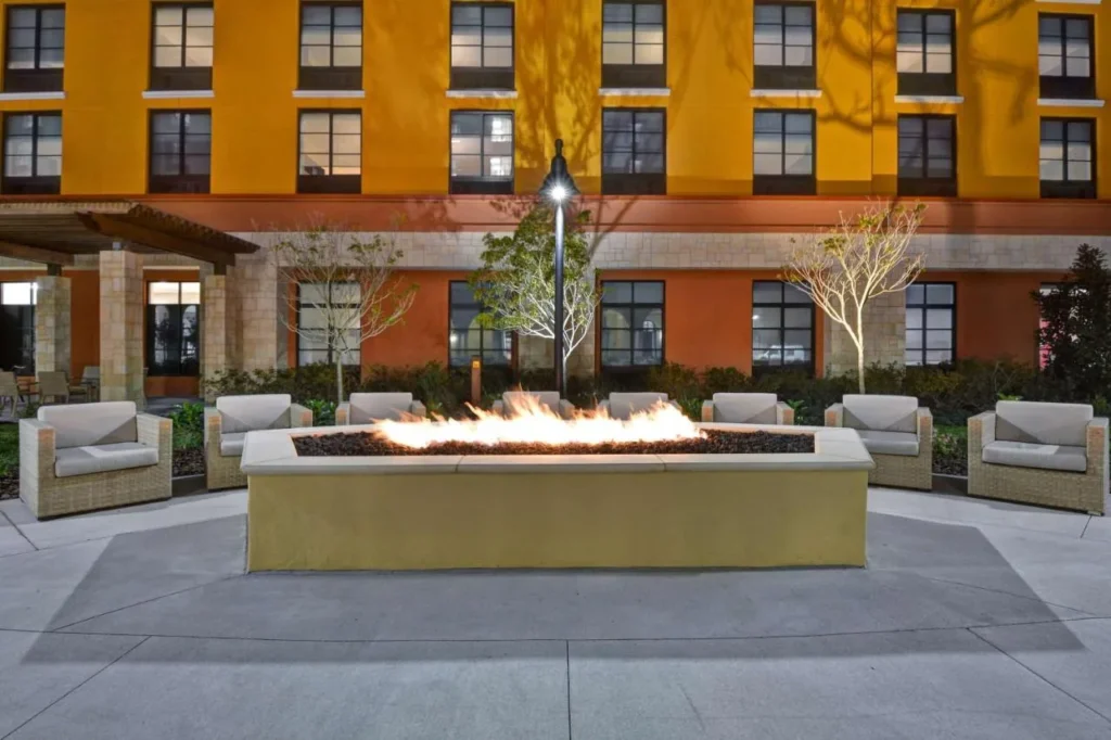 Hoyo de gas largo con sillones de mimbre en el Courtyard en Home2 Suites Flamingo Crossings