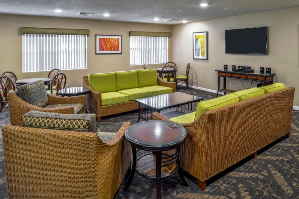Salón con sofás de mimbre, mesas de juego y TV en Hilton Vacation Club Polynesian Isles Kissimmee