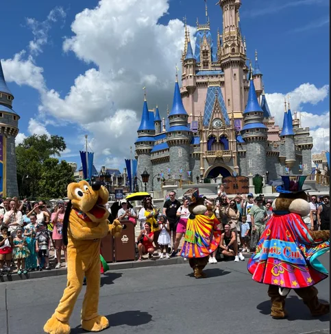 Pluto y personajes disfrazados de Disney bailando para las multitudes frente al Castillo de Cenicienta en Magic Kingdom