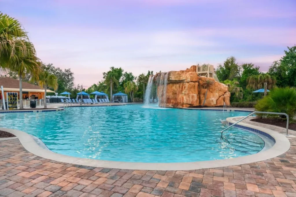 Piscina principal con una cascada de roca y torre deslizante, caba&ntilde;as detr&aacute;s, en Mystic Dunes Resort