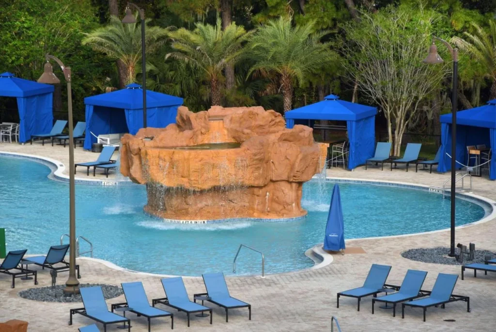 Piscina principal con cascada de roca, caba&ntilde;as azules y tumbonas en Wyndham Garden Lake Buena Vista