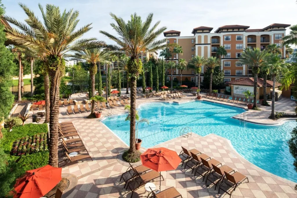 Main pool with palms, red umbrellas and suite buildings at Floridays Resort Orlando