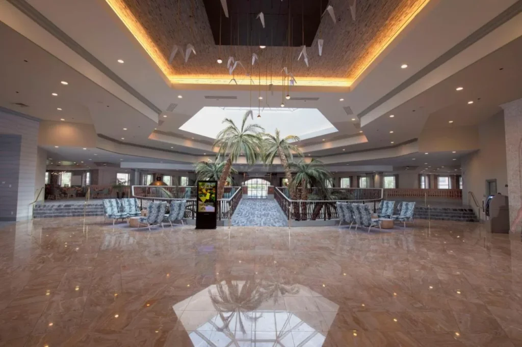 Atrio de m&aacute;rmol con palmeras, claraboya y sillones azules en Caribe Royale Orlando