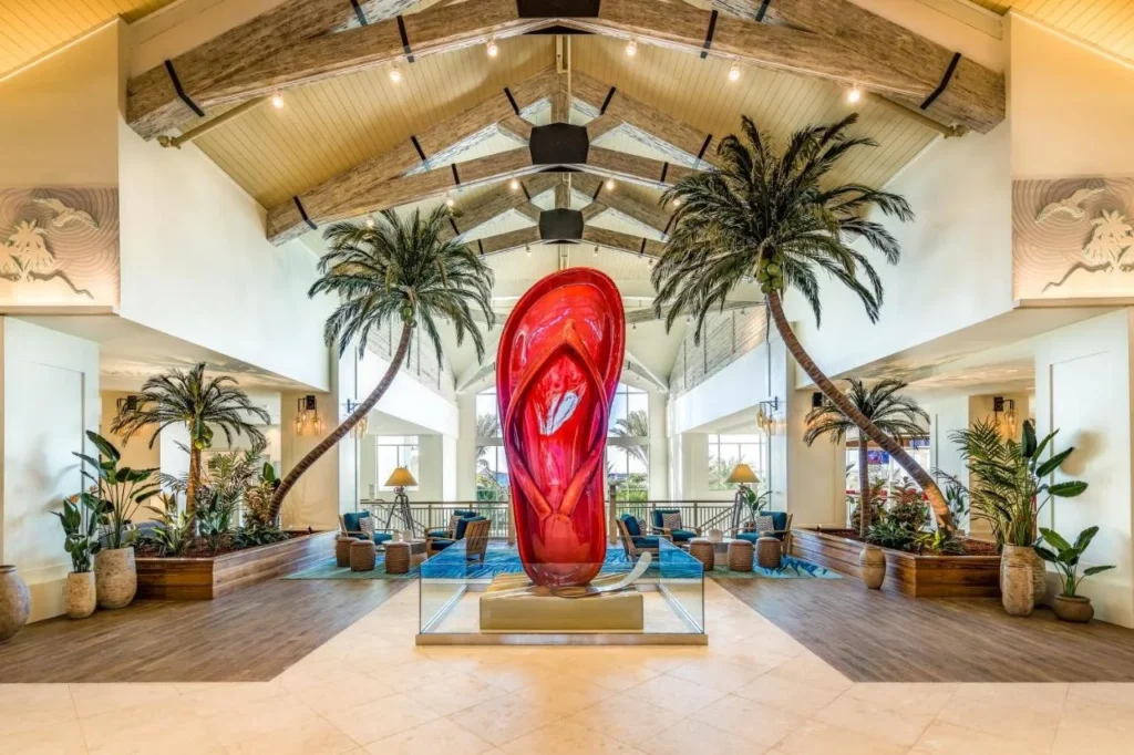Margaritaville Resort Orlando lobby with palm trees, beamed ceiling and a giant red flip-flop sculpture