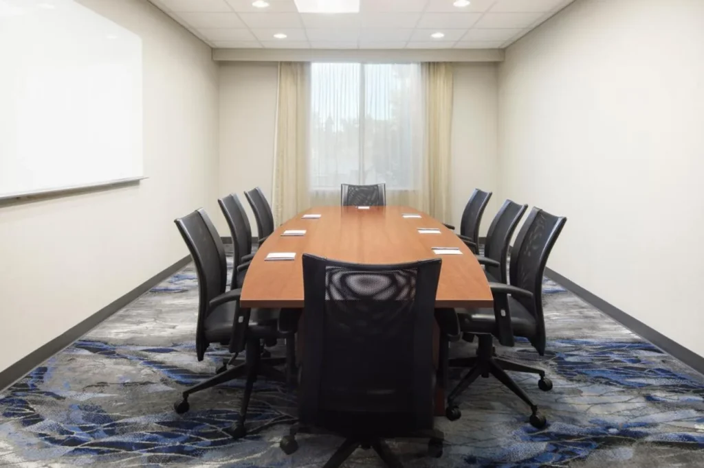 Sala de reuniones con una larga mesa de madera y sillas de malla en Fairfield Kissimmee/Celebration