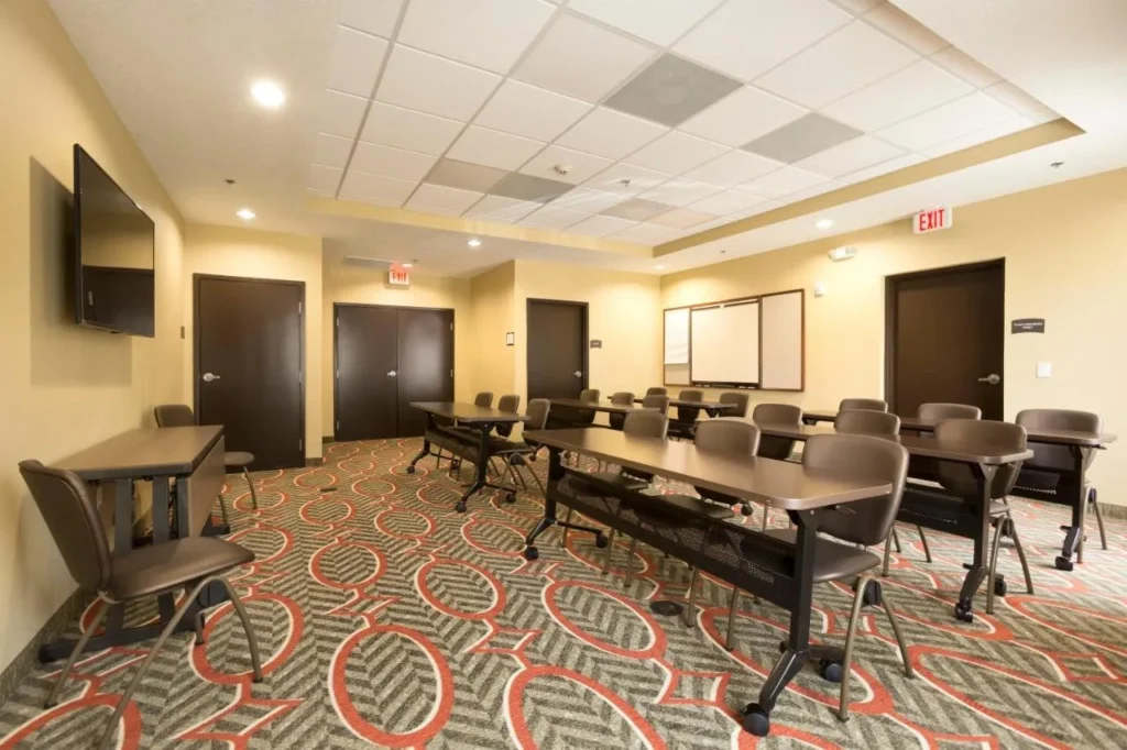 Sala de reuniones con mesas, sillas, TV de pared y pizarra en Staybridge Suites Orlando at SeaWorld