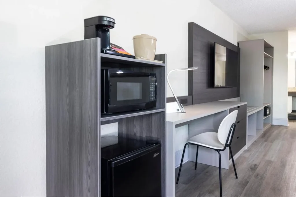 Microondas, mininevera, cafetera y escritorio sobre pisos imitación madera en una habitación del Avanti International Resort