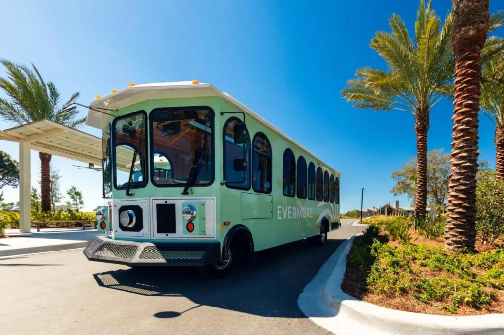 Mint-green Evermore trolley parked under palm trees at Evermore Orlando Resort