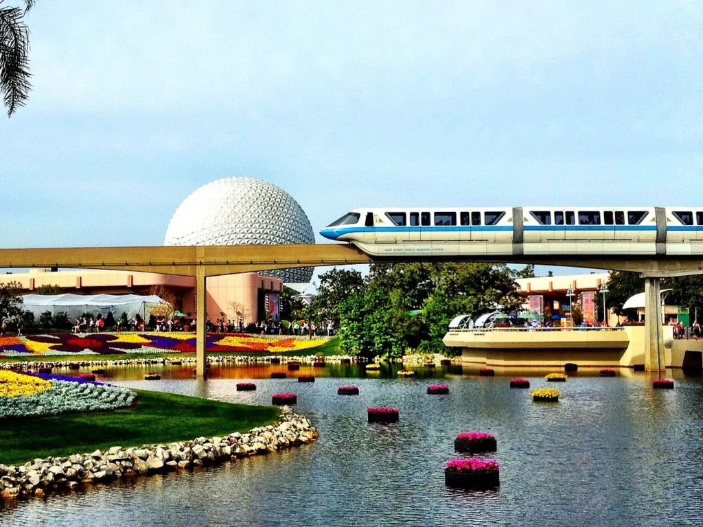 Monorail passing Spaceship Earth above flower beds and floating planters during EPCOT's Flower and Garden Festival