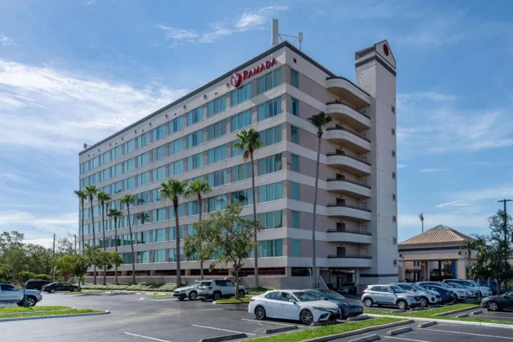Torre de hotel de varios pisos con palmeras y un estacionamiento en Ramada by Wyndham Kissimmee Gateway