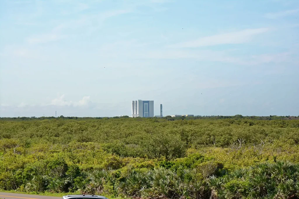 NASA Vehicle Assembly Construyendo en el horizonte m&aacute;s all&aacute; del matorral costero cerca de Playa Playalinda, Canaveral National Seashore
