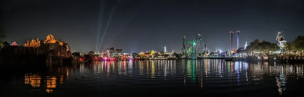 Panorama nocturno a trav&eacute;s de la laguna de las Islands of Adventure con bucles de monta&ntilde;a Hulk y tierras iluminadas