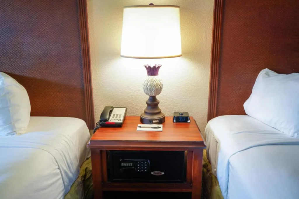 Mesita de noche con lámpara, teléfono y caja fuerte entre dos camas en Rosen Inn at Pointe Orlando