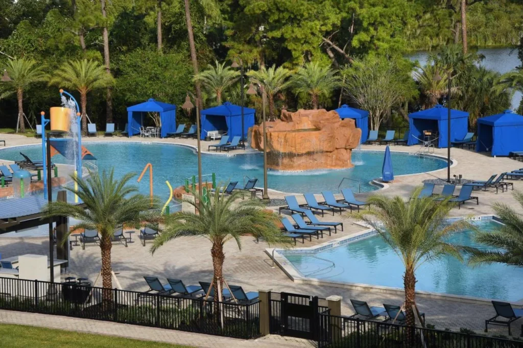 Oasis pool with a rock waterfall, blue cabanas and loungers at Wyndham Lake Buena Vista