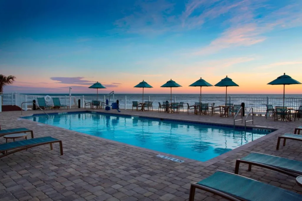 Oceanfront pool with teal umbrellas at sunset at SpringHill Suites by Marriott New Smyrna Beach