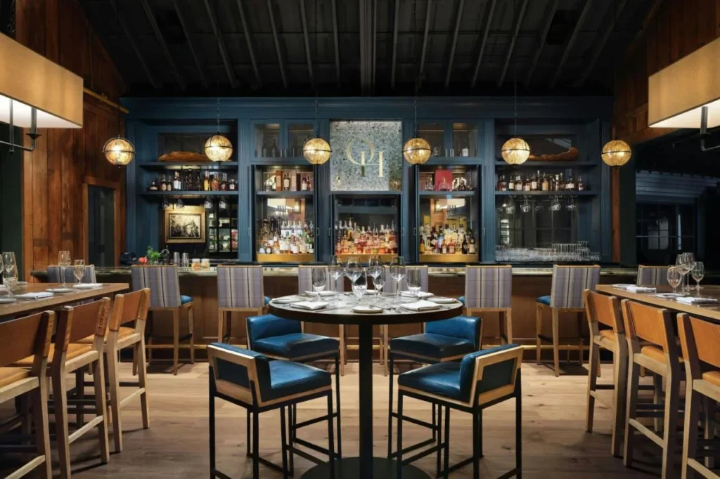 Old Hickory Steakhouse bar con sillas de cuero azul y estantes retroiluminados de espíritus en Gaylord Palms