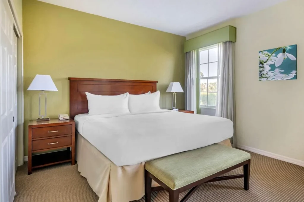 Dormitorio de estilo antiguo con una cama grande, cabecera de madera y banco en Mystic Dunes Resort