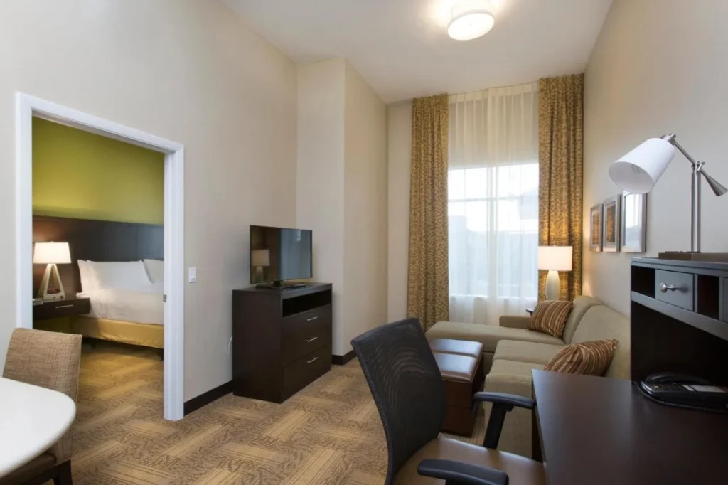 Suite de un dormitorio con sofá y puerta abierta, Staybridge Suites Orlando at SeaWorld